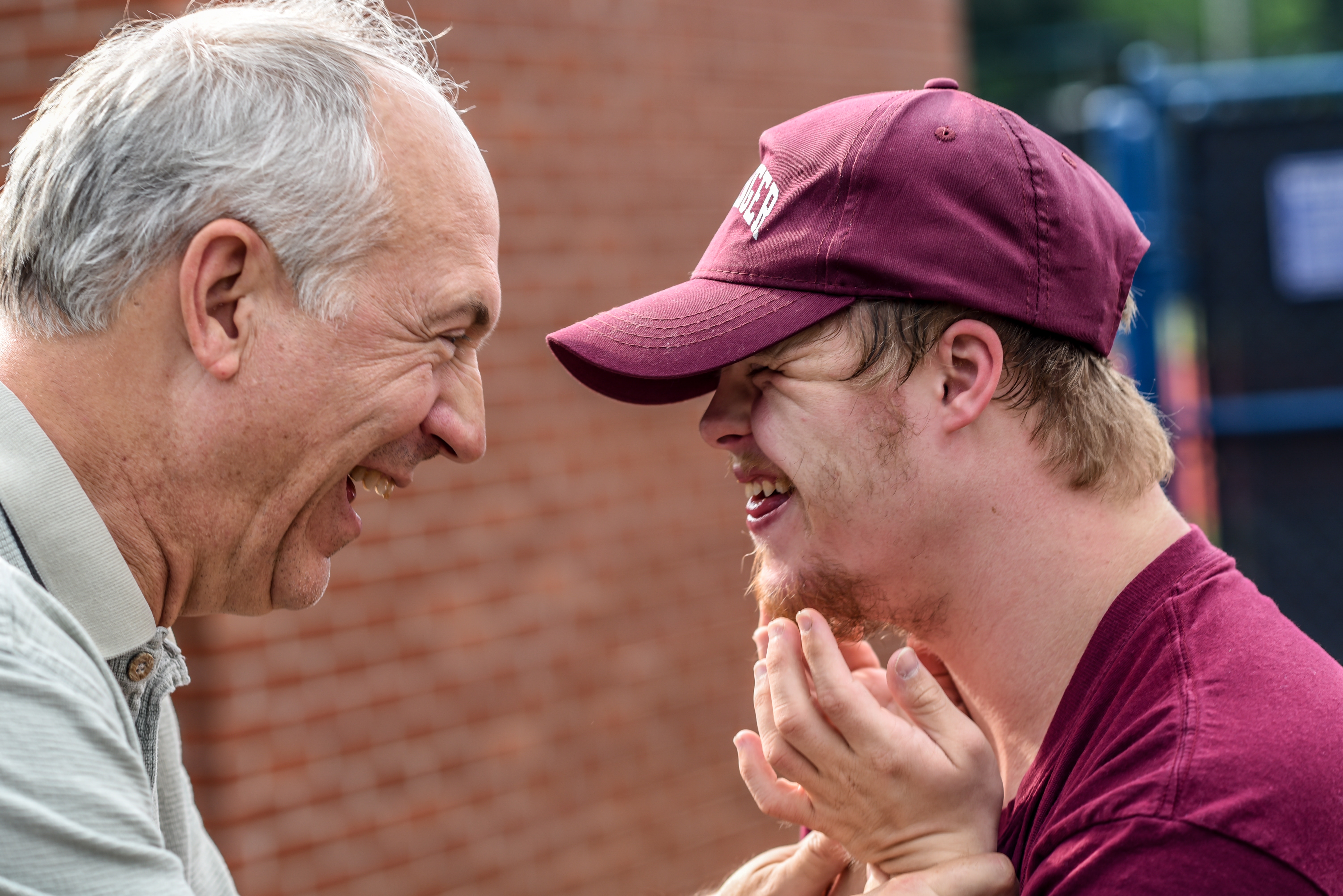 An adolescent and an older man laughing together