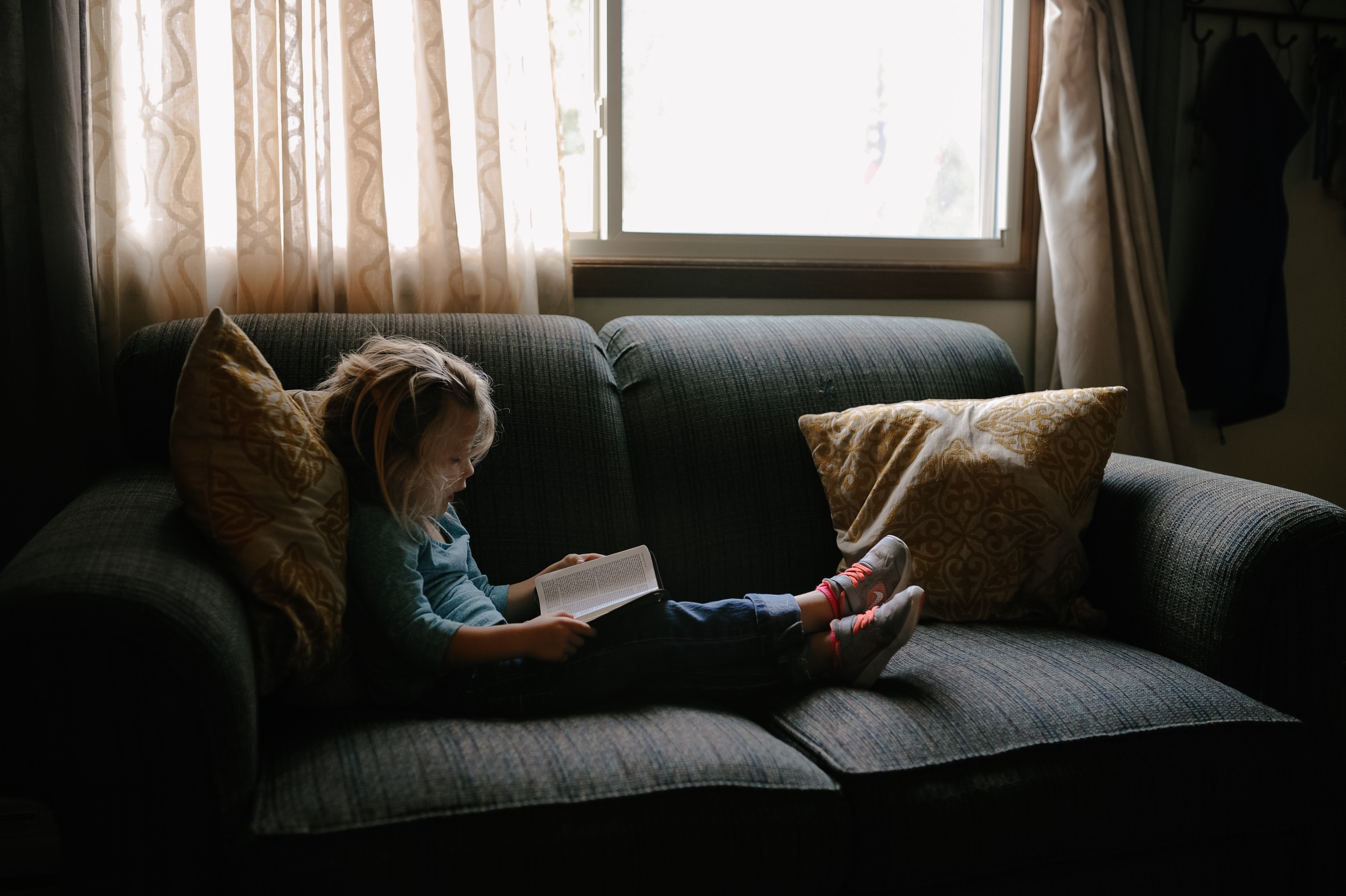 Little girl reading in a couch