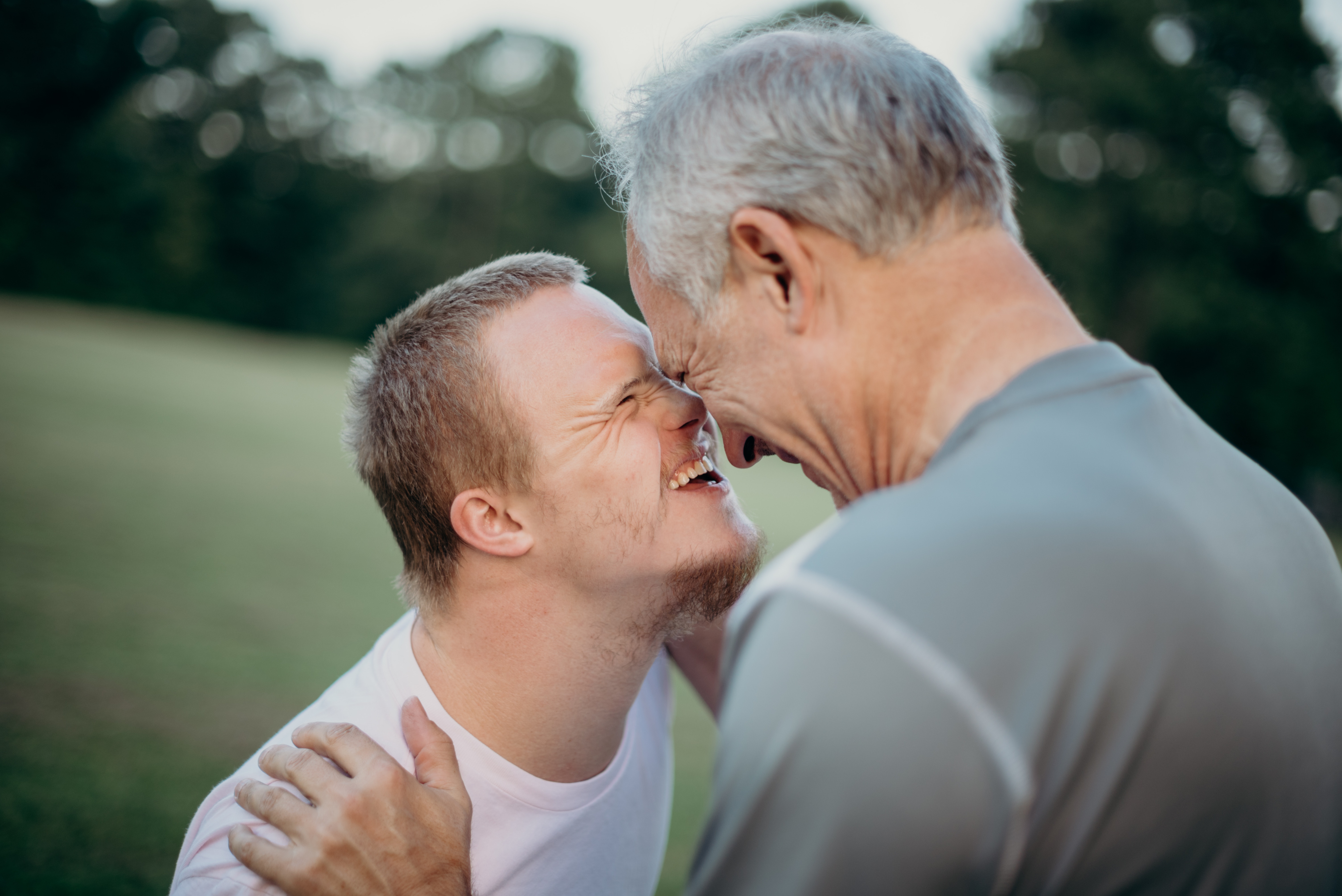 An adolescent and an older man laughing together