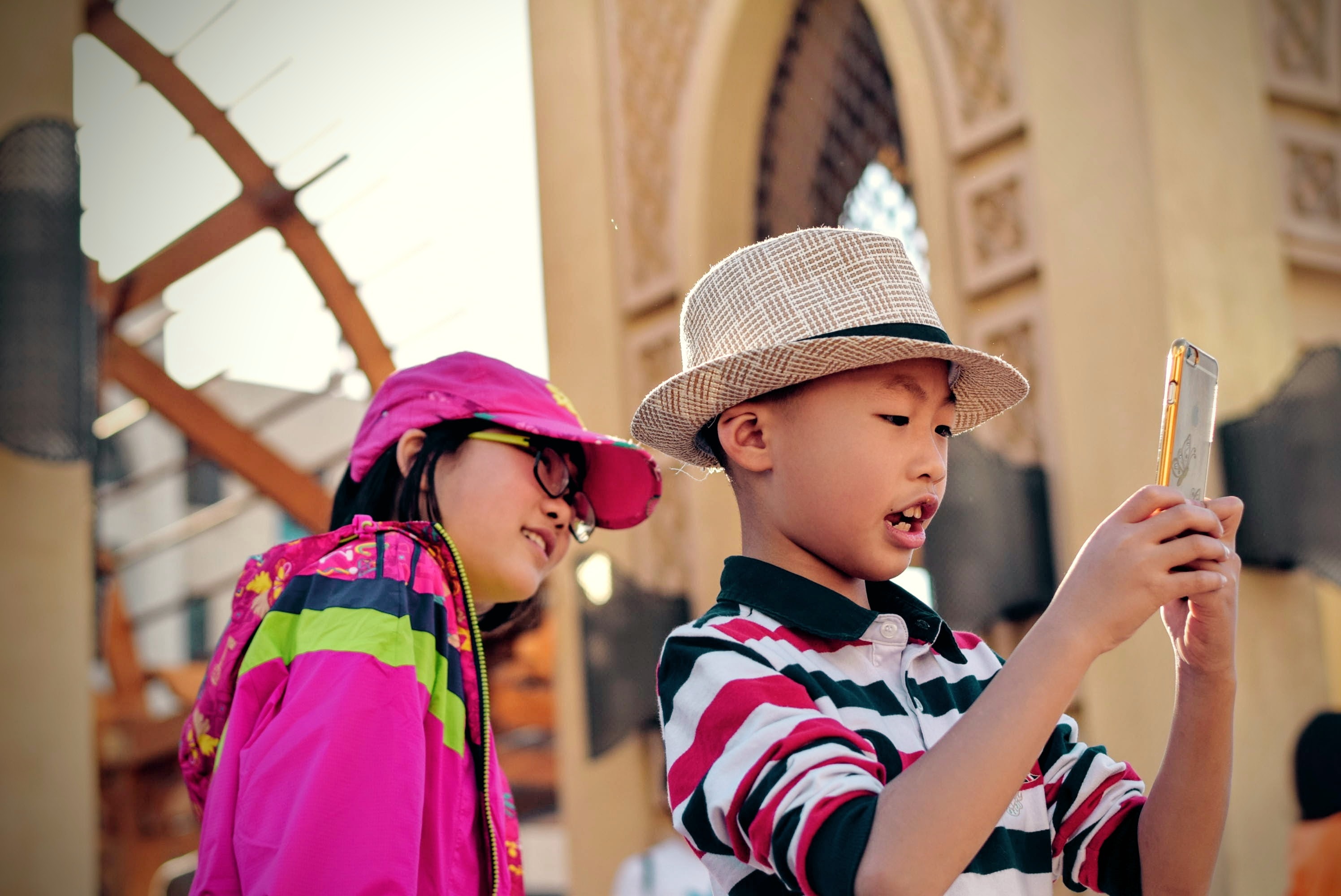 Boy and girl with hats taking picture with smartphone