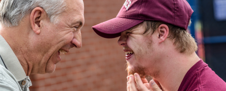 An adolescent and an older man laughing together